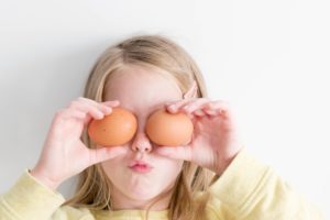 girl holding eggs on her eyes