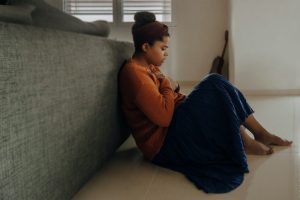 Girl sitting against couch looking stressed