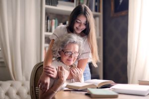 Grandmother and granddaughter hugging and reading a book