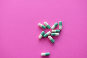 Blue and white pills scattered on pink background