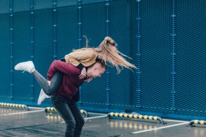 Boy carrying girl on back spinning her around outside