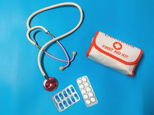 Stethoscope, first aid kit, and medicine on blue background