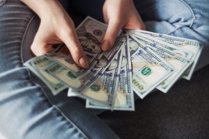Closeup of hands holding a fan of 100-dollar bills