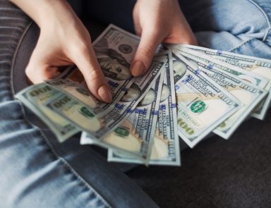 Closeup of hands holding a fan of 100-dollar bills