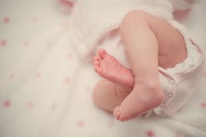 Closeup of baby laying on bed with feet up