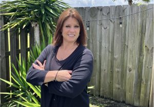 Teacher smiling outside in front of fence