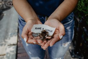 Person holding coins with a note saying, "Make a change"