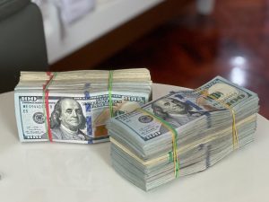 Two stacks of $100 bills with rubber bands around them on a table