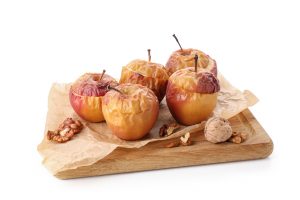 Baked apples sitting on a wooden cutting board