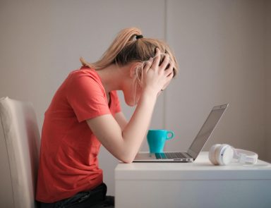 Person sitting at computer looking stressed out with head in their hands