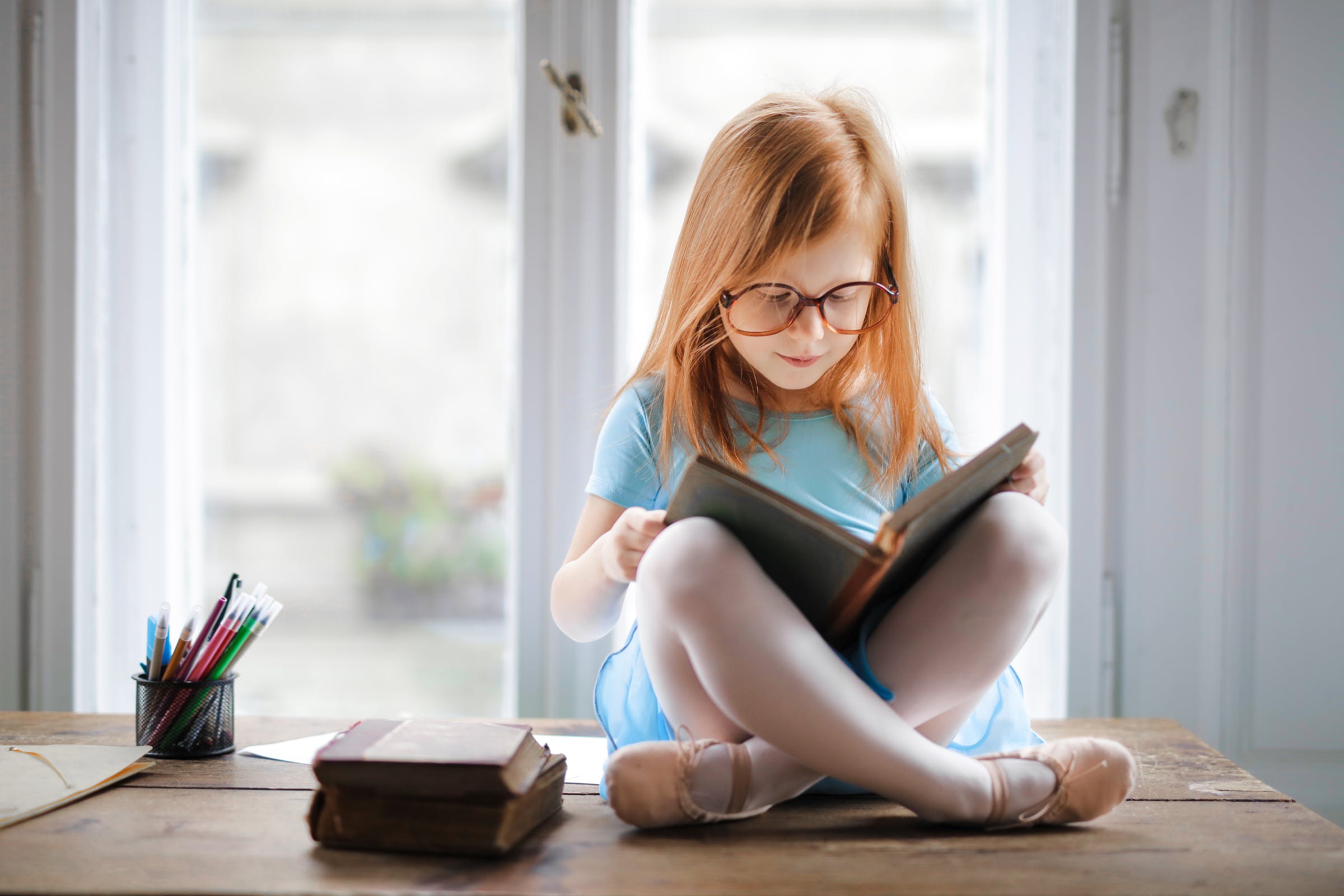 Little girl with glasses reading book