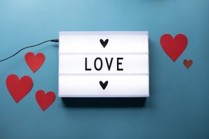 Light up sign spelling "love" on blue background with hearts