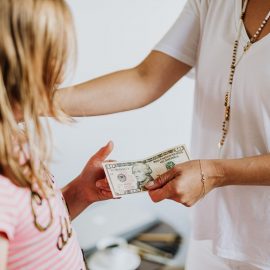 Mother handing daughter a $10 bill