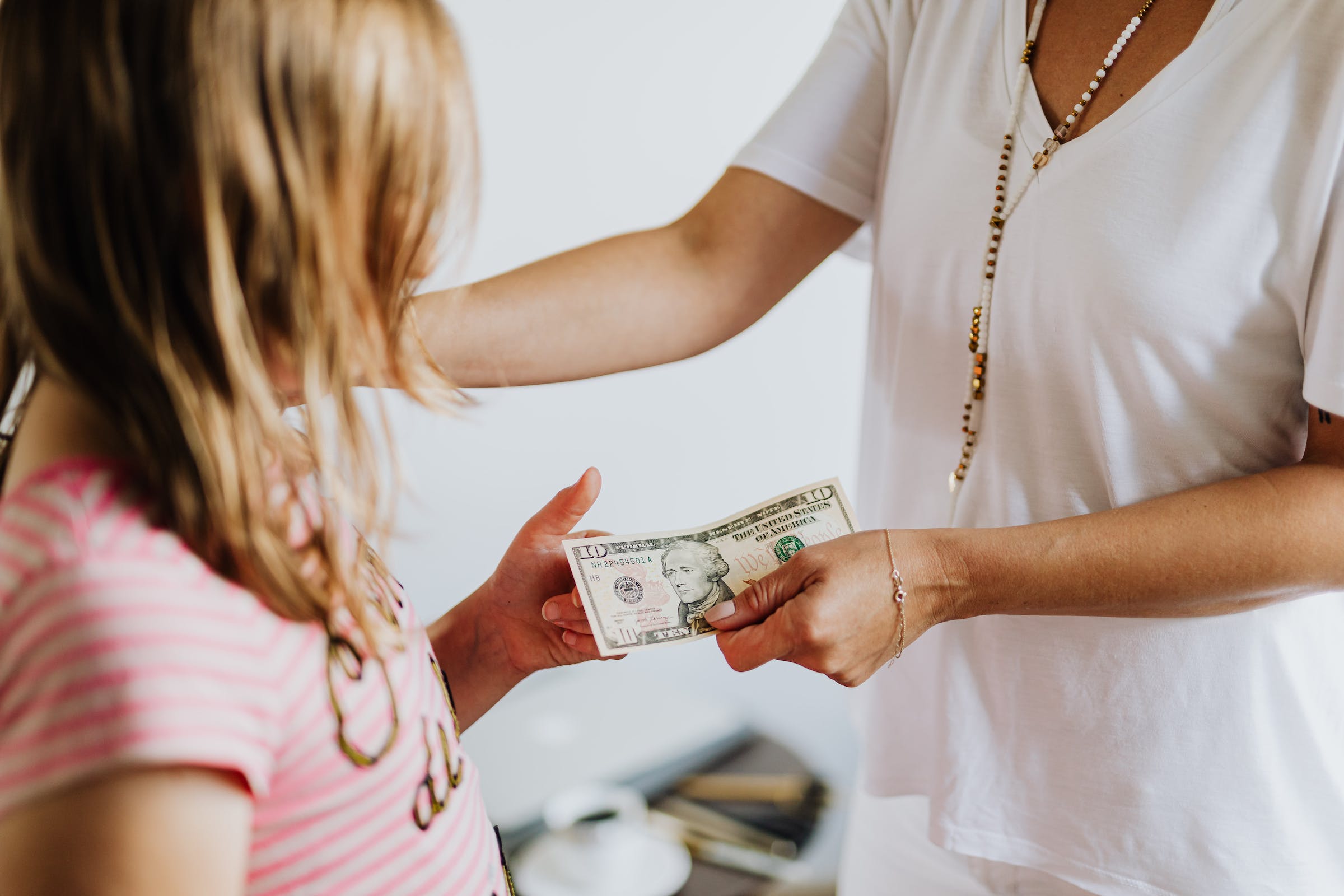 Mother handing daughter a $10 bill