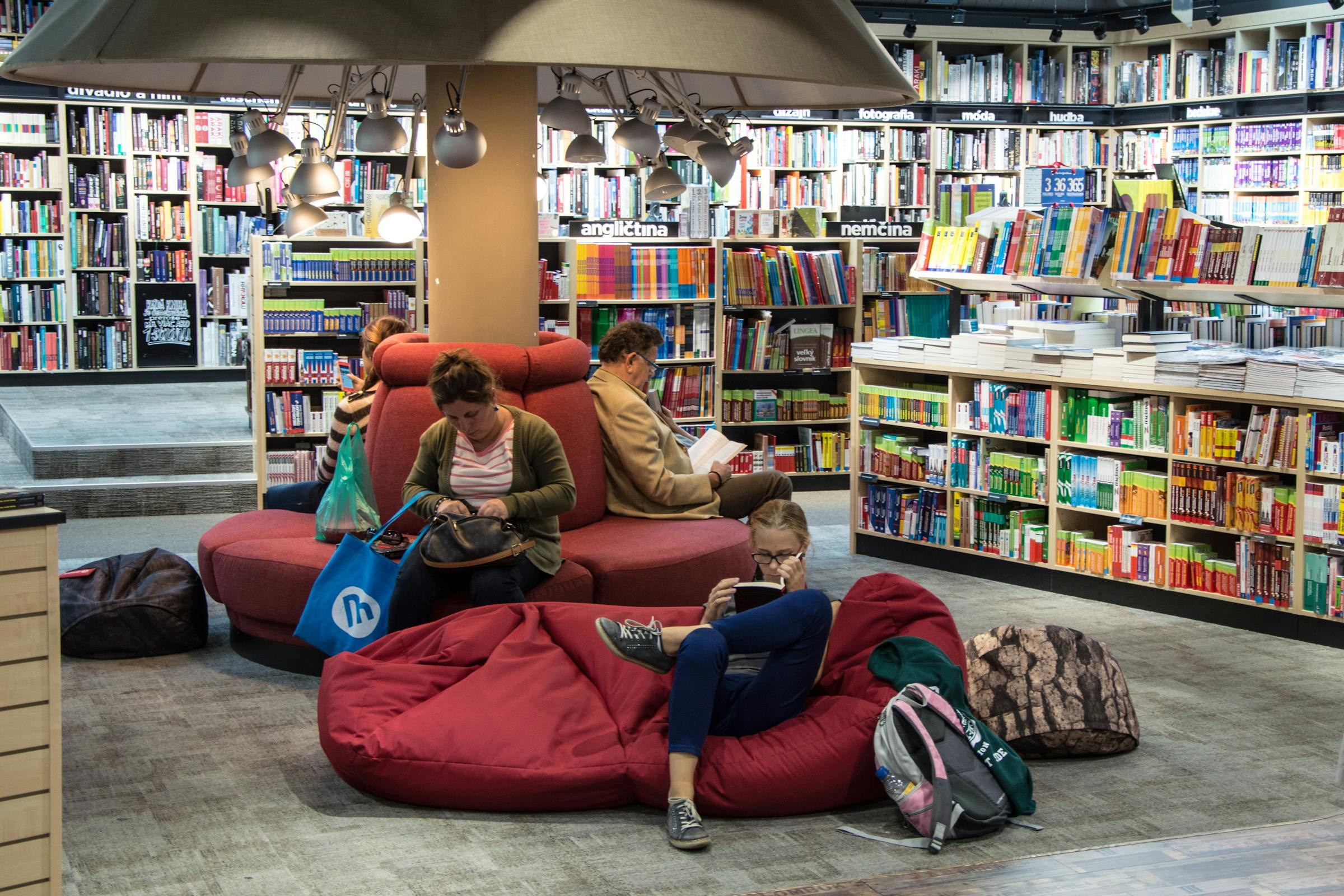 People sitting on bean bag chairs reading in a library
