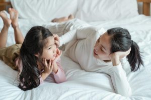 Mother and daughter laying in bed talking