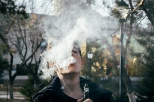 Teen boy vaping blowing cloud of smoke