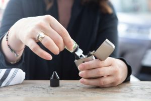 Teen girl pouring vape juice into her vape