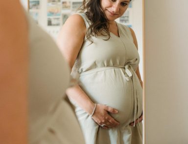 Woman looking at pregnant stomach in mirror