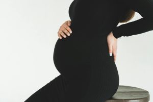Pregnant woman in black dress holding her back