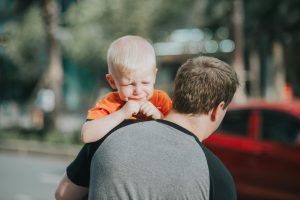 Dad holding crying little boy