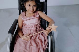 Little girl in a wheel chair wearing a pink dress