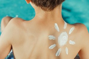 Kid with sunblock on his back in the shape of a sun