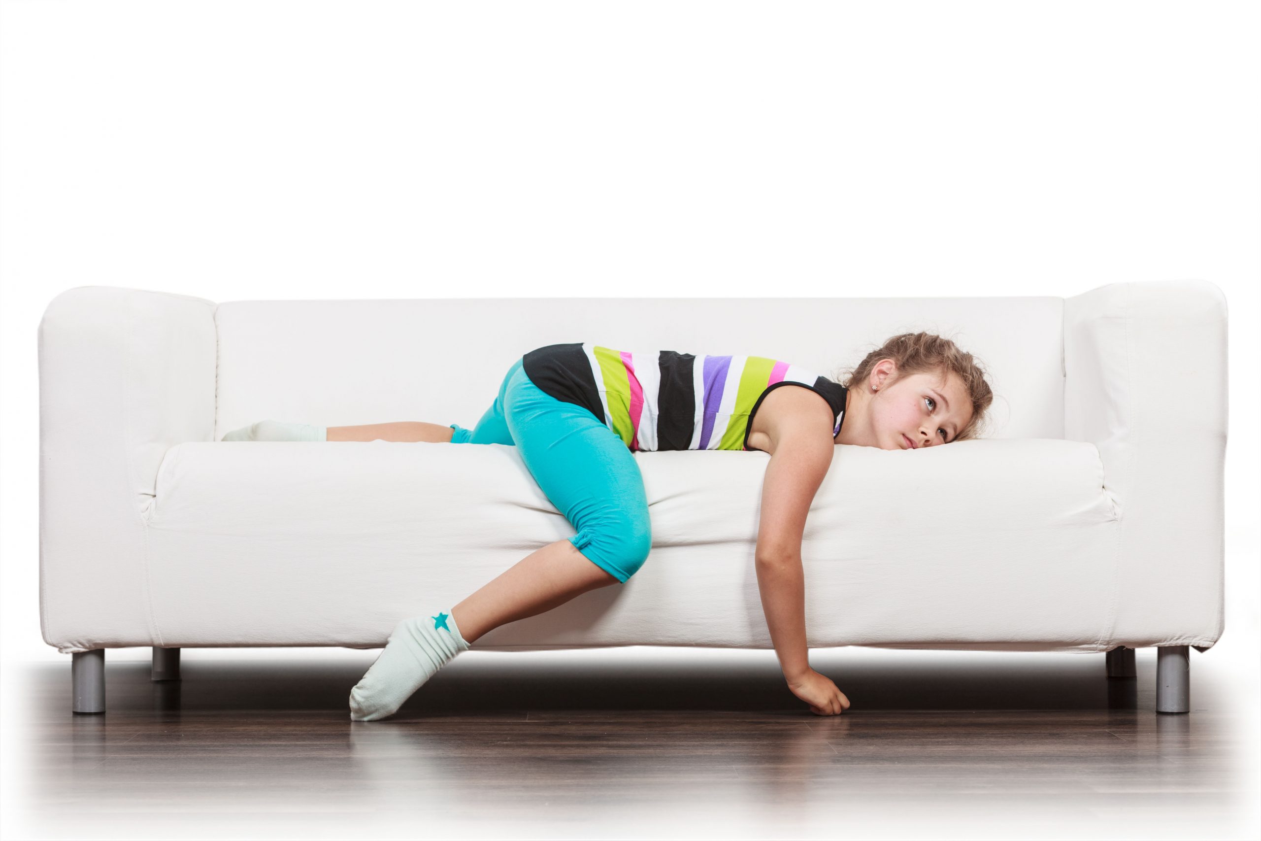 Young girl laying on white couch on her stomach