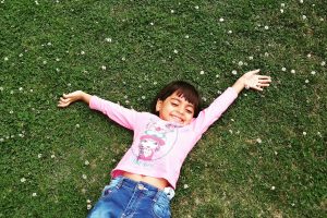 Child laying in grass smiling